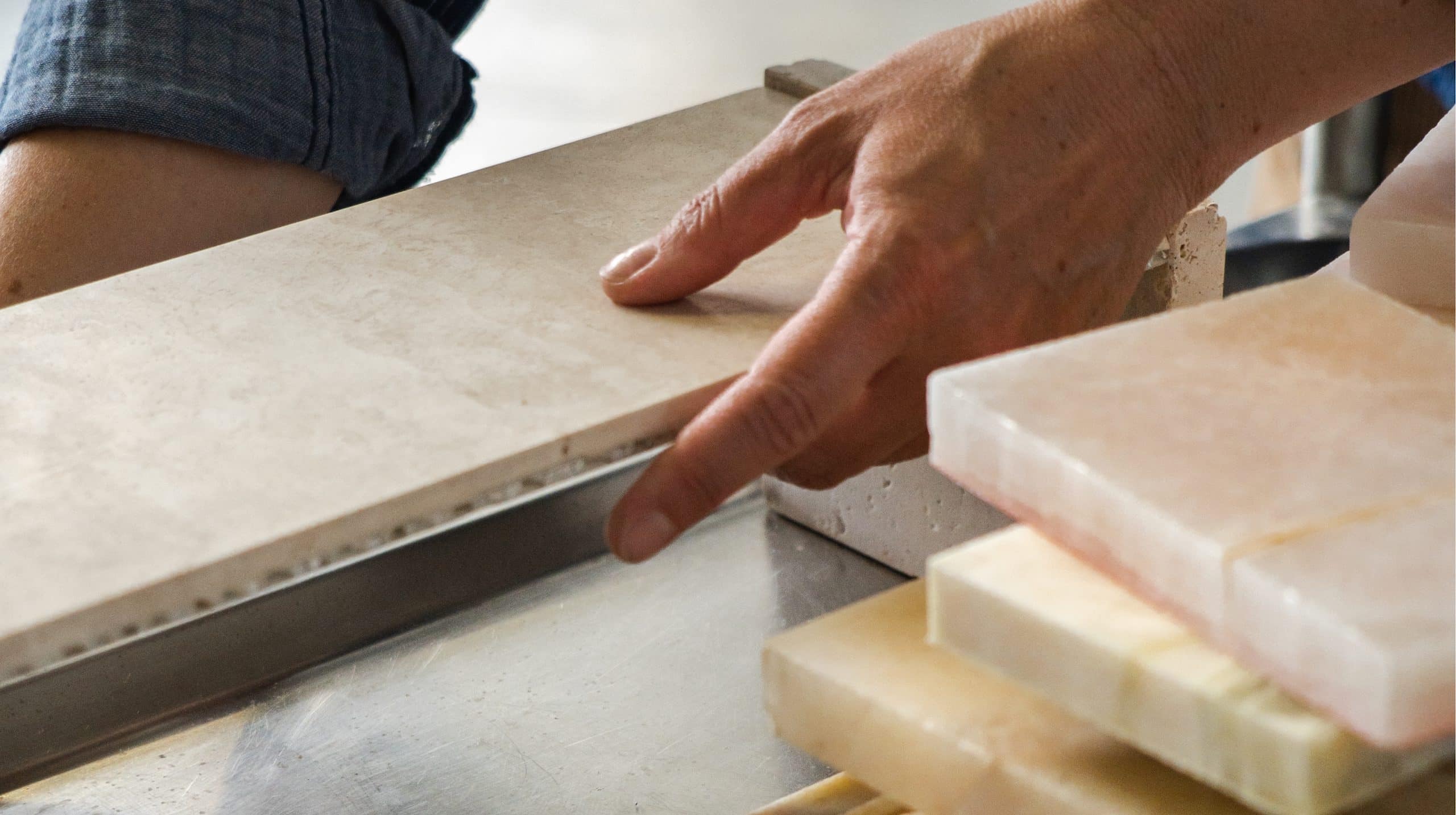 Hands comparing stone slabs and material samples during custom design development