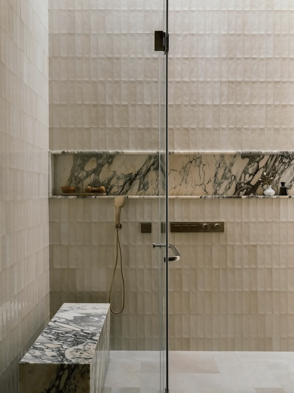 Integrated marble shower niche with tiled bathroom wall and glass screen
