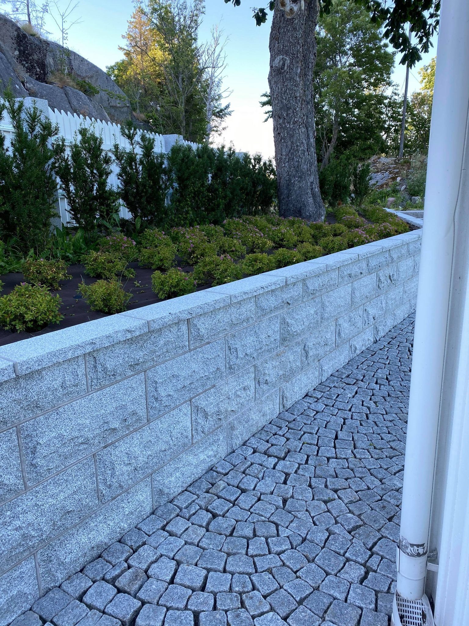 Light grey granite retaining wall and curved paving